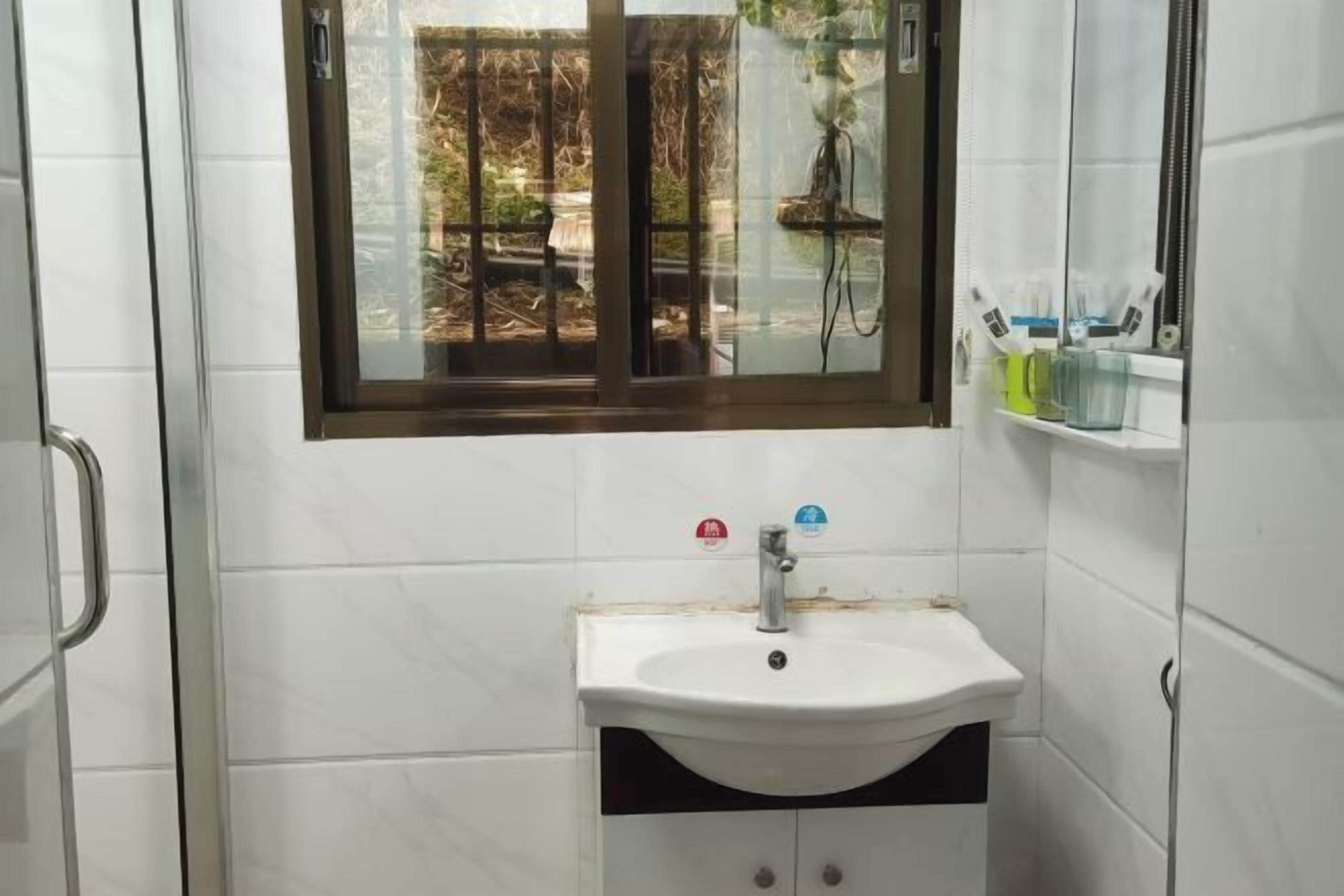 Un baño con un lavamanos blanco, una ventana y un espejo.