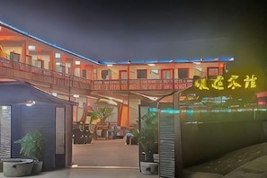 Un hôtel doté d’une entrée couverte, d’un espace extérieur aménagé pour s’asseoir et d’une enseigne lumineuse au néon.