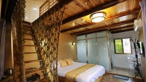 Ein Zimmer aus Holz mit einem Bett, einer Treppe und einem Badezimmer mit Waschbecken und Spiegel.