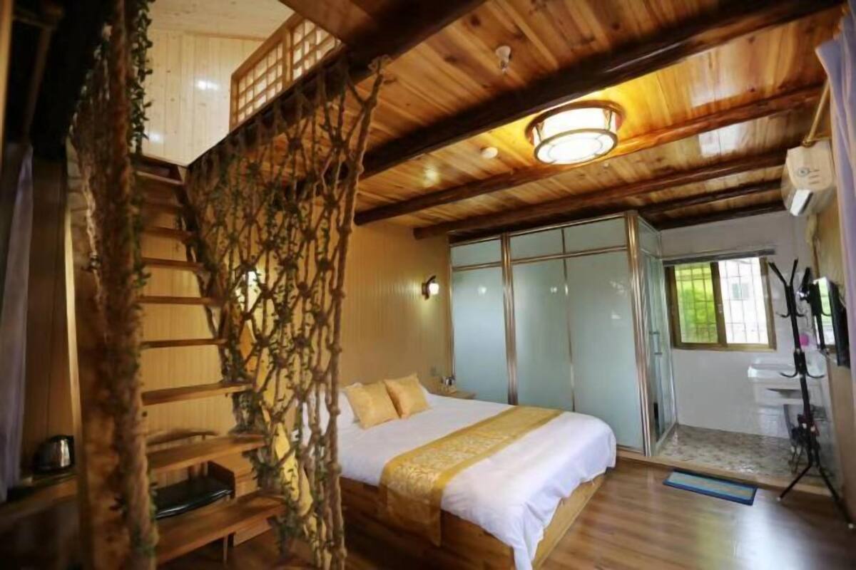 A wooden room with a bed, a staircase, and a bathroom with a sink and mirror.