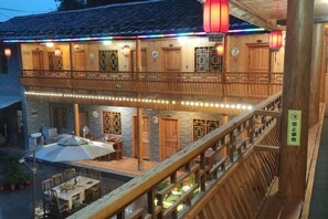 A traditional wooden building with a balcony, outdoor seating, and string lights. - Nuantu Inn (Nanjing County)
