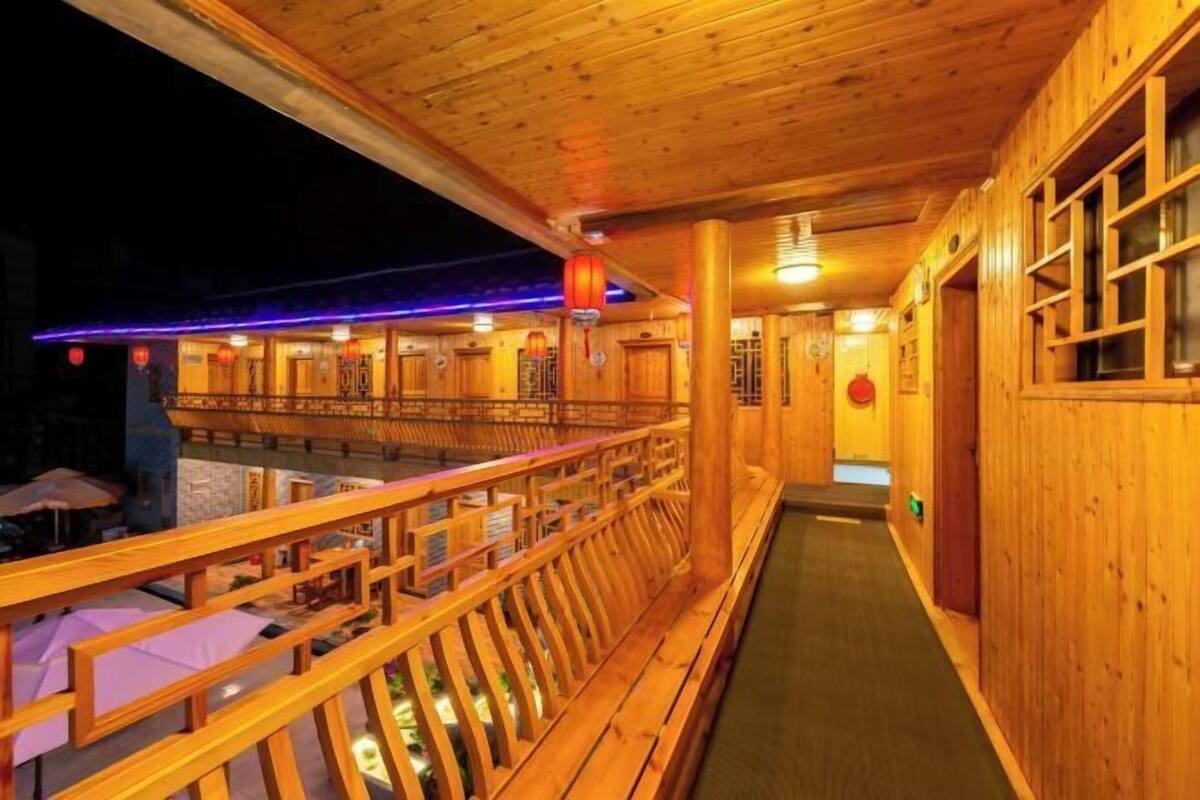 A wooden interior with a balcony, wooden railings, and a view of the outside.