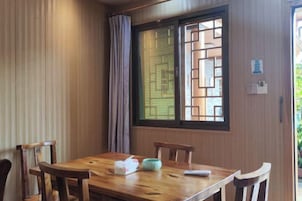 Una mesa de comedor de madera con cuatro sillas, una ventana con un diseño geométrico y una cortina.