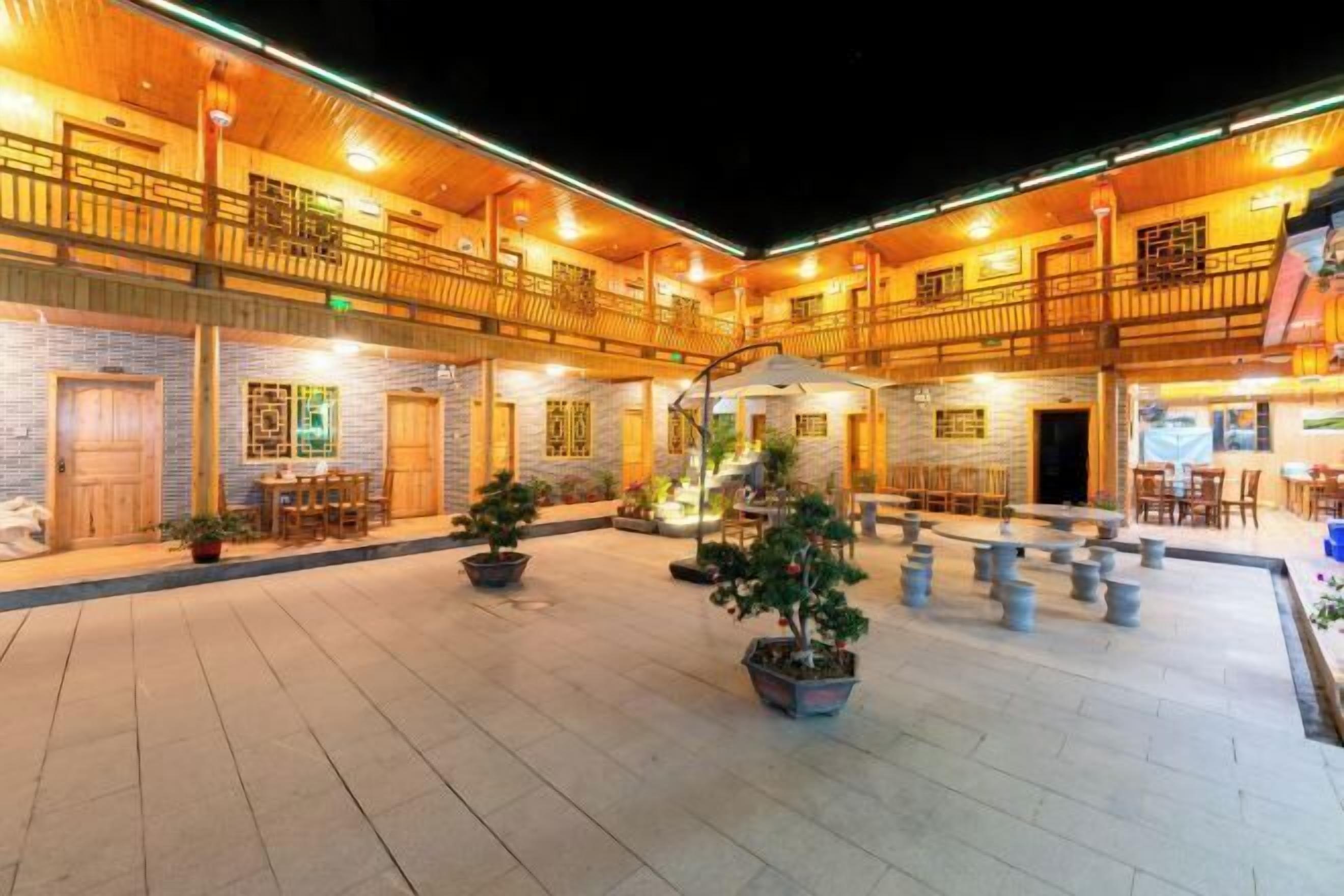 A spacious courtyard with multiple seating areas, wooden railings, and potted plants.