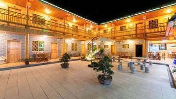 A spacious courtyard with multiple seating areas, wooden railings, and potted plants.