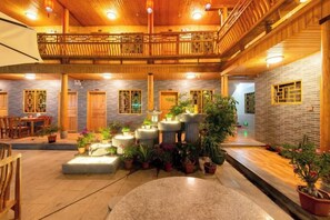 A spacious courtyard with a wooden balcony, potted plants, and a seating area. - Nuantu Inn (Nanjing County)