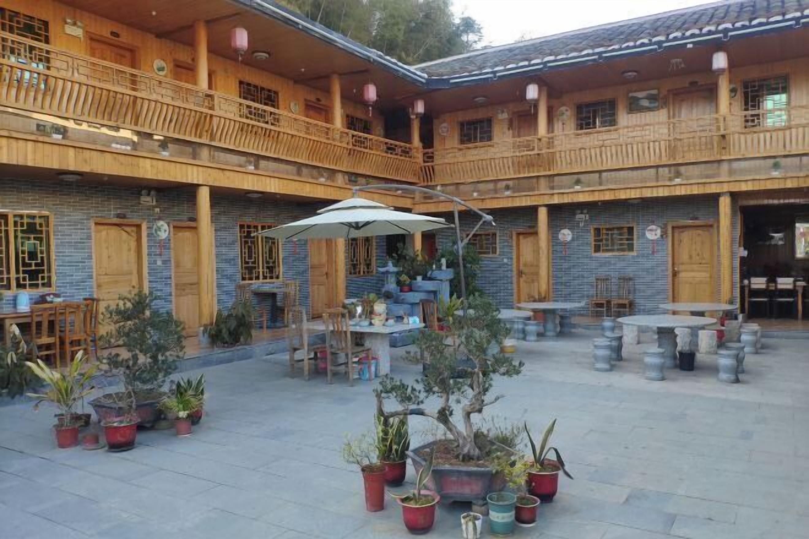 Une cour dotée de balcons en bois, de plantes en pot et d’espaces aménagés pour s’asseoir à l’extérieur.
