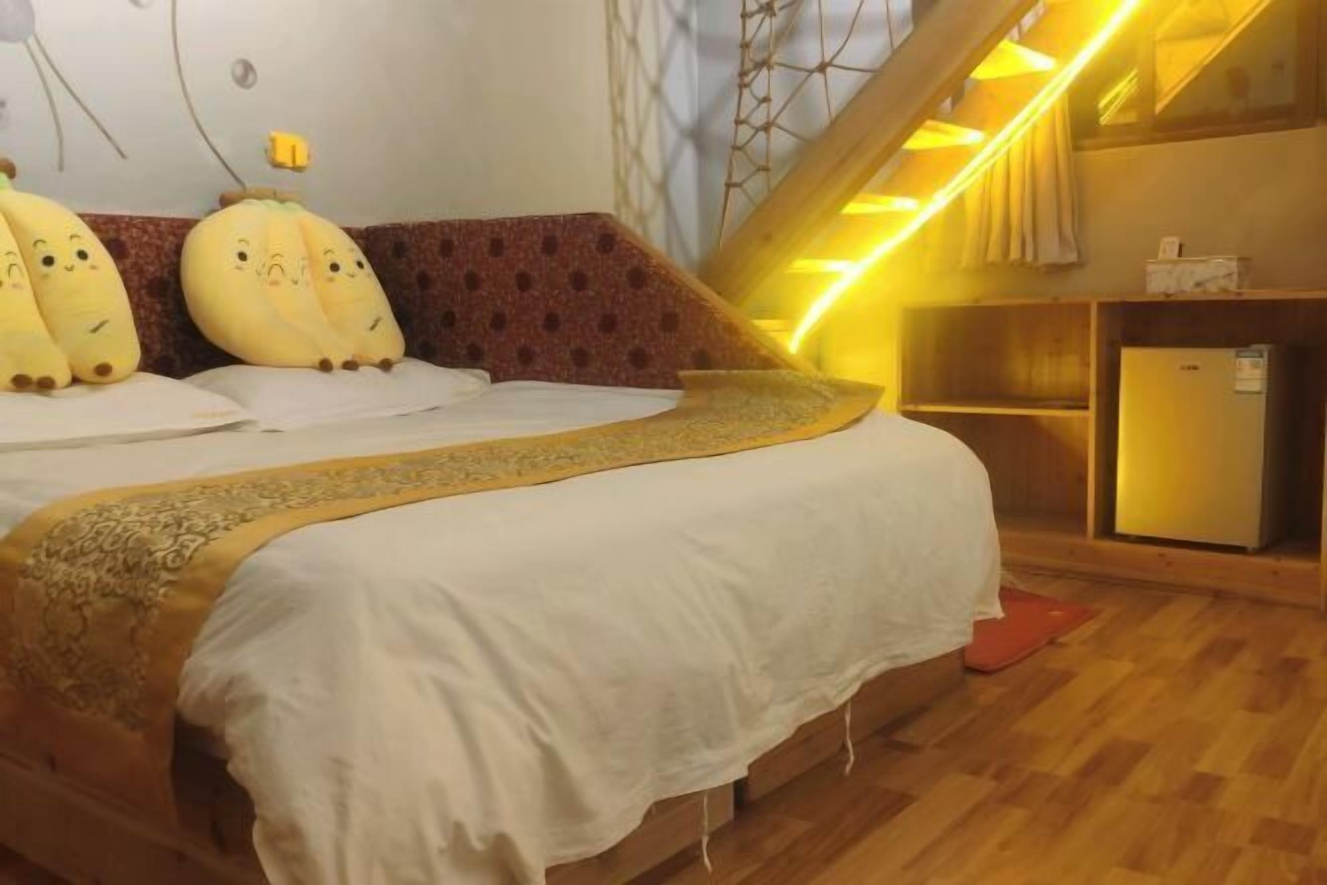 A bedroom with a bed, a wooden headboard, a bedside table, a nightstand, and a small cabinet.