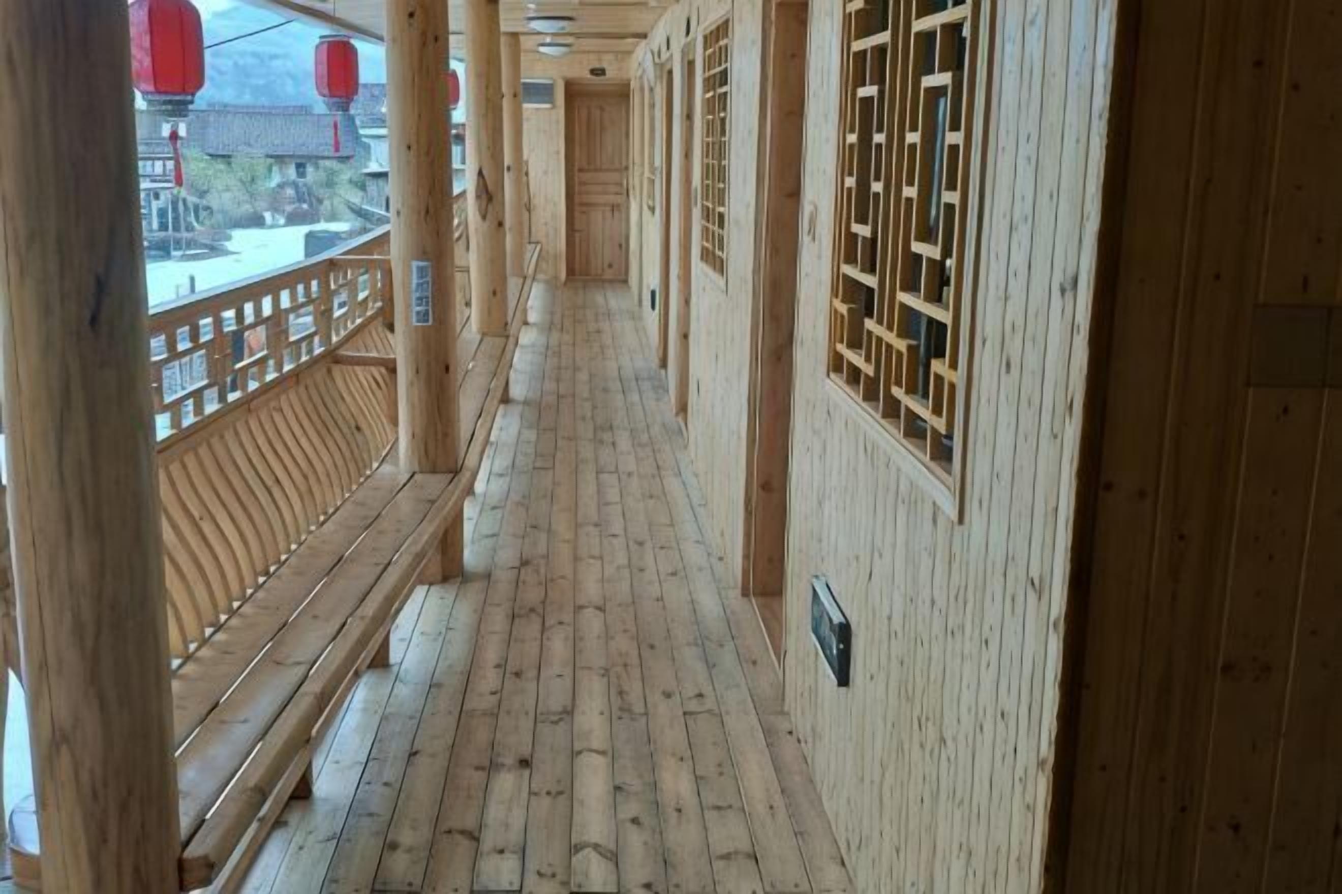 Un couloir en bois, doté de bancs, de rampes en bois et de fenêtres de style traditionnel.