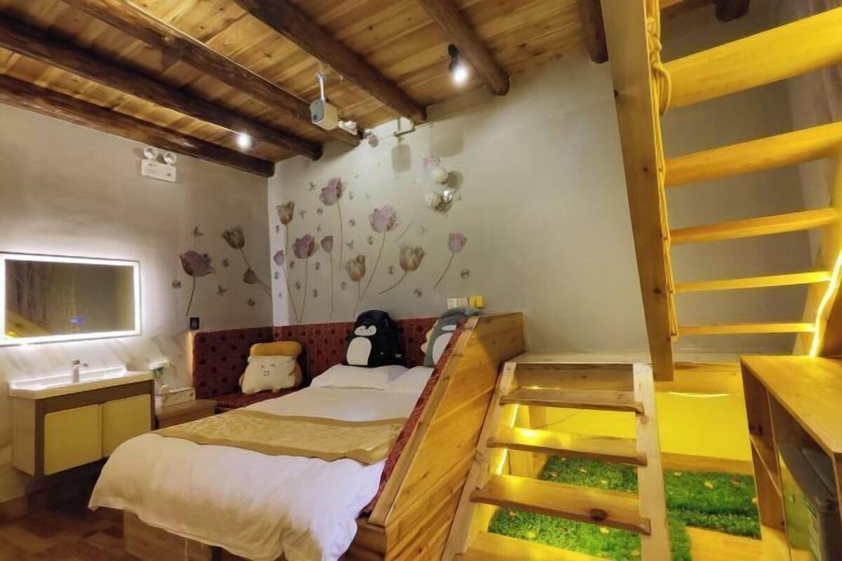 A bedroom with a wooden bunk bed, a small desk, a mirror, and a wall with floral decorations.
