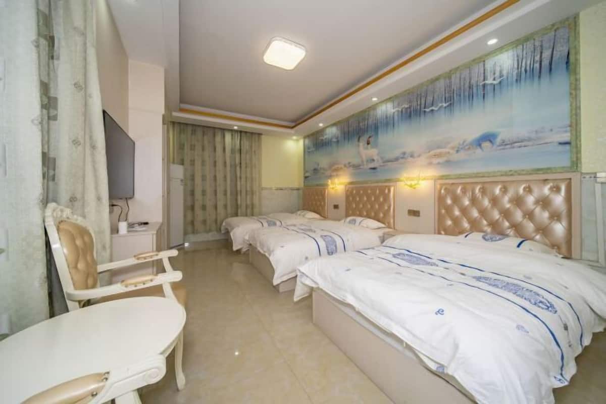 Quarto de hotel com três camas, uma mesa de jantar e uma cadeira.