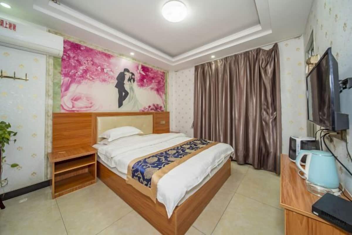 Quarto com cama de madeira, televisão, chaleira e um quadro na parede.