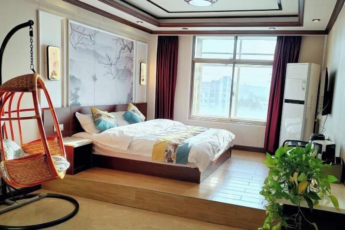 Quarto com cama, cadeira suspensa, janela e planta.
