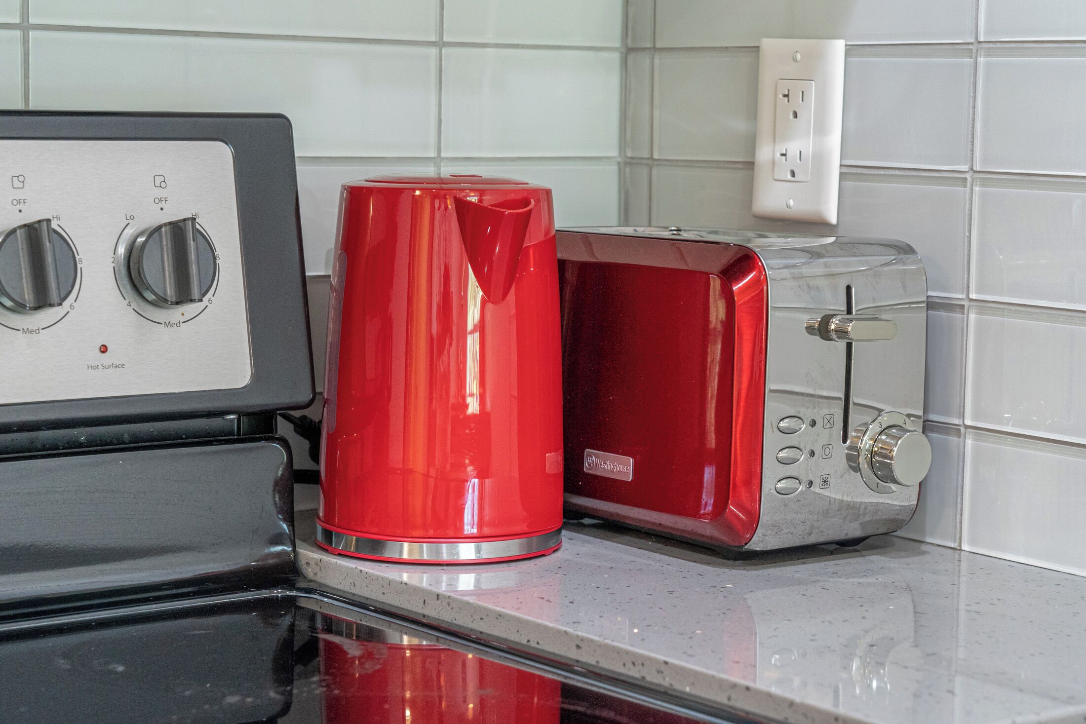 Una cucina con un bollitore rosso, un tostapane e un fornello.