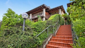 A staircase leading to a building with a balcony, surrounded by greenery. - Grotten Loft with lake view and pool (Toscolano Maderno)