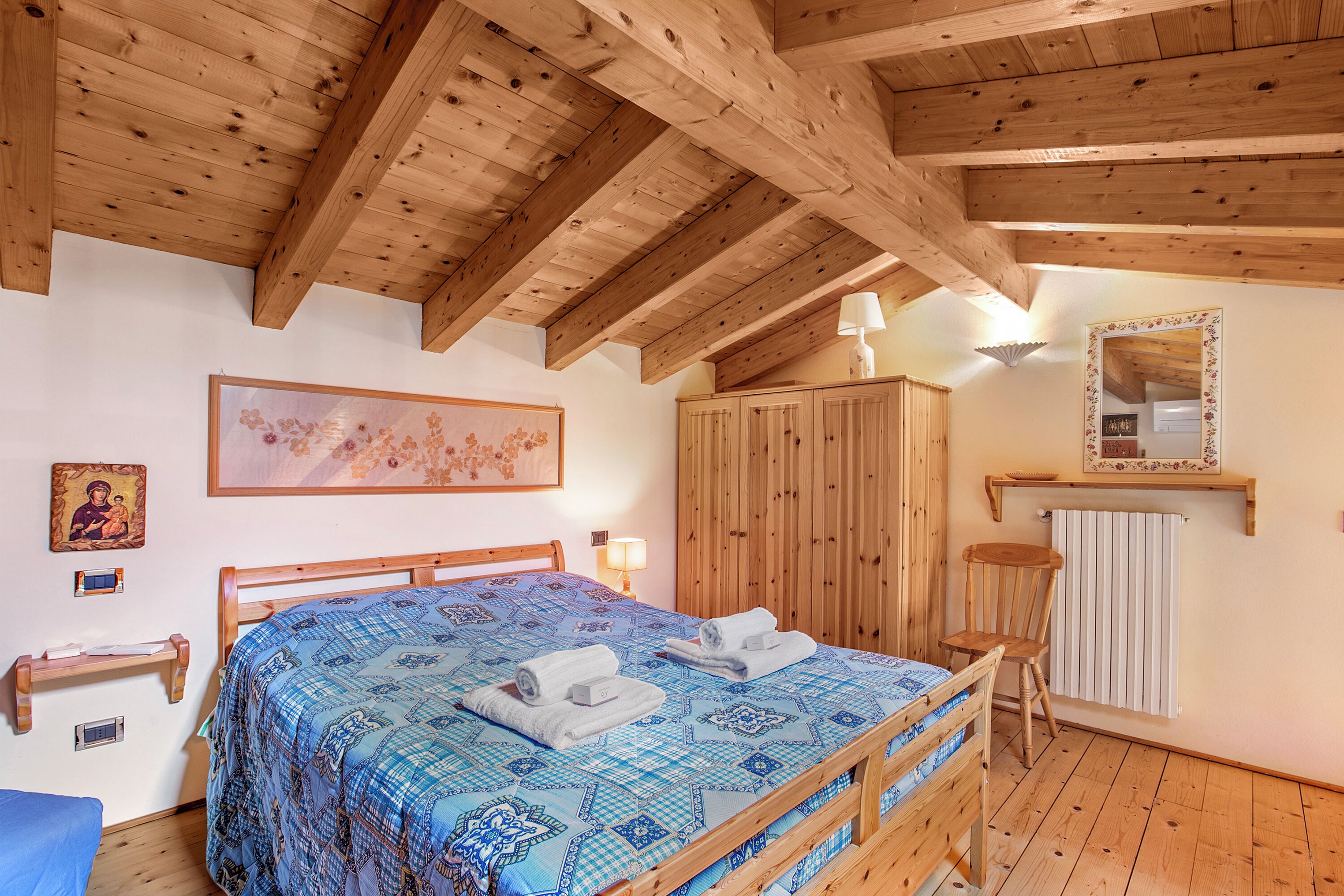 Une chambre à coucher en bois, avec un lit, une armoire, une chaise et un radiateur.