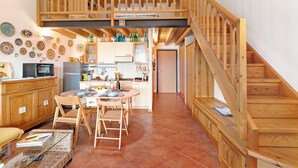 A spacious kitchen with wooden cabinets, a dining area with a table and chairs, and a wooden staircase. - Grotten Loft with lake view and pool (Toscolano Maderno)