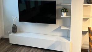 En moderne stue med et fladskærms TV ophængt på et hvidt tv-møbel.