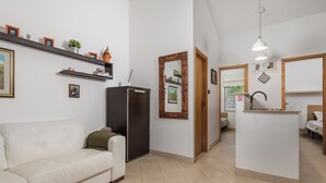 Una sala de estar moderna con un sofá, una mesa de centro, un refrigerador y una zona de cocina con un lavamanos y encimera.