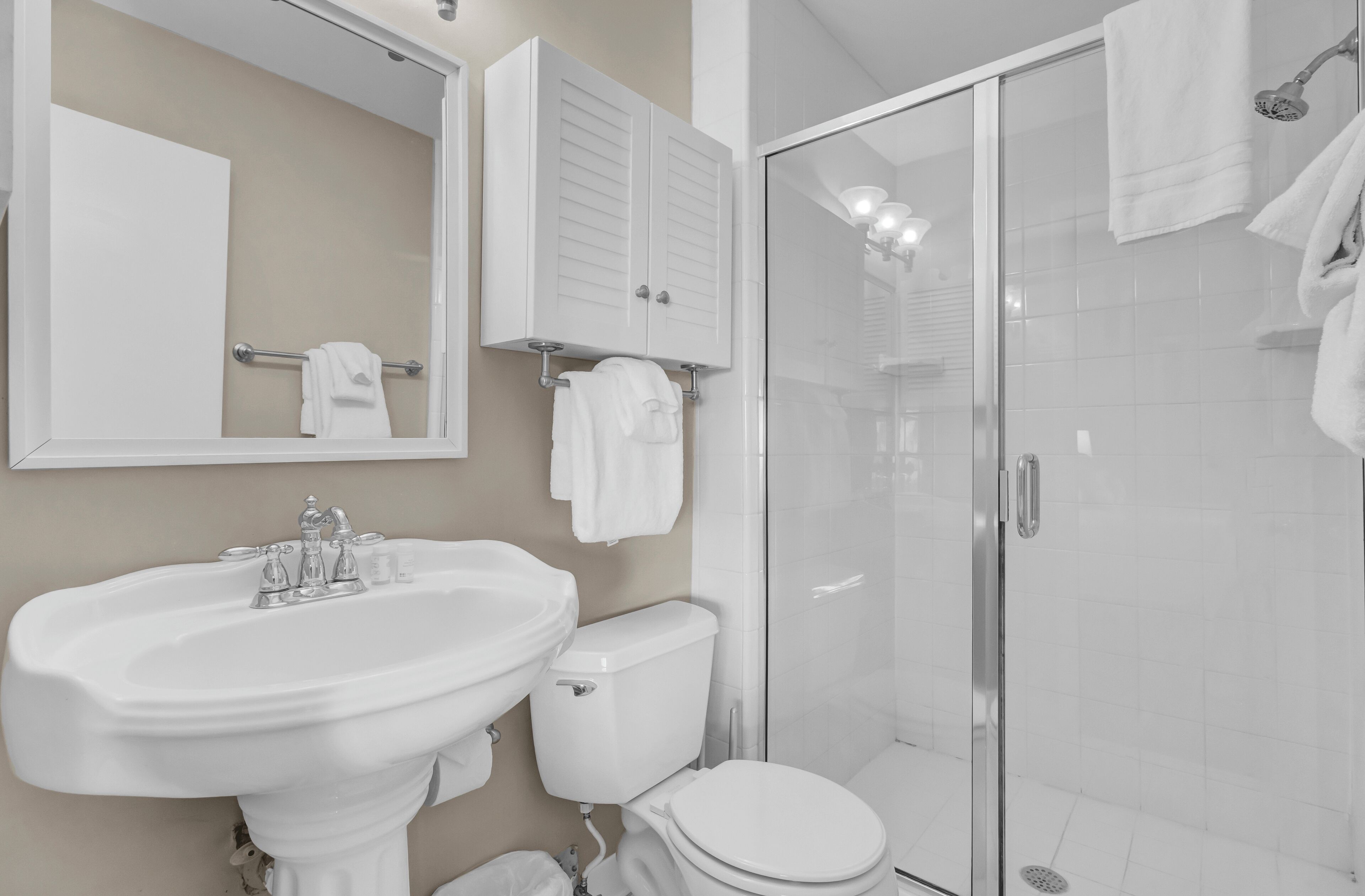 A bathroom with a sink, toilet, and glass shower enclosure.