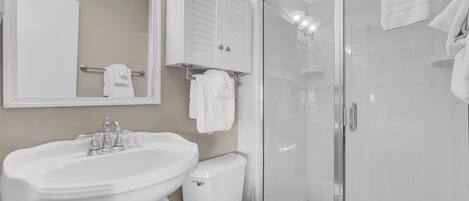 A bathroom with a sink, toilet, and glass shower enclosure.