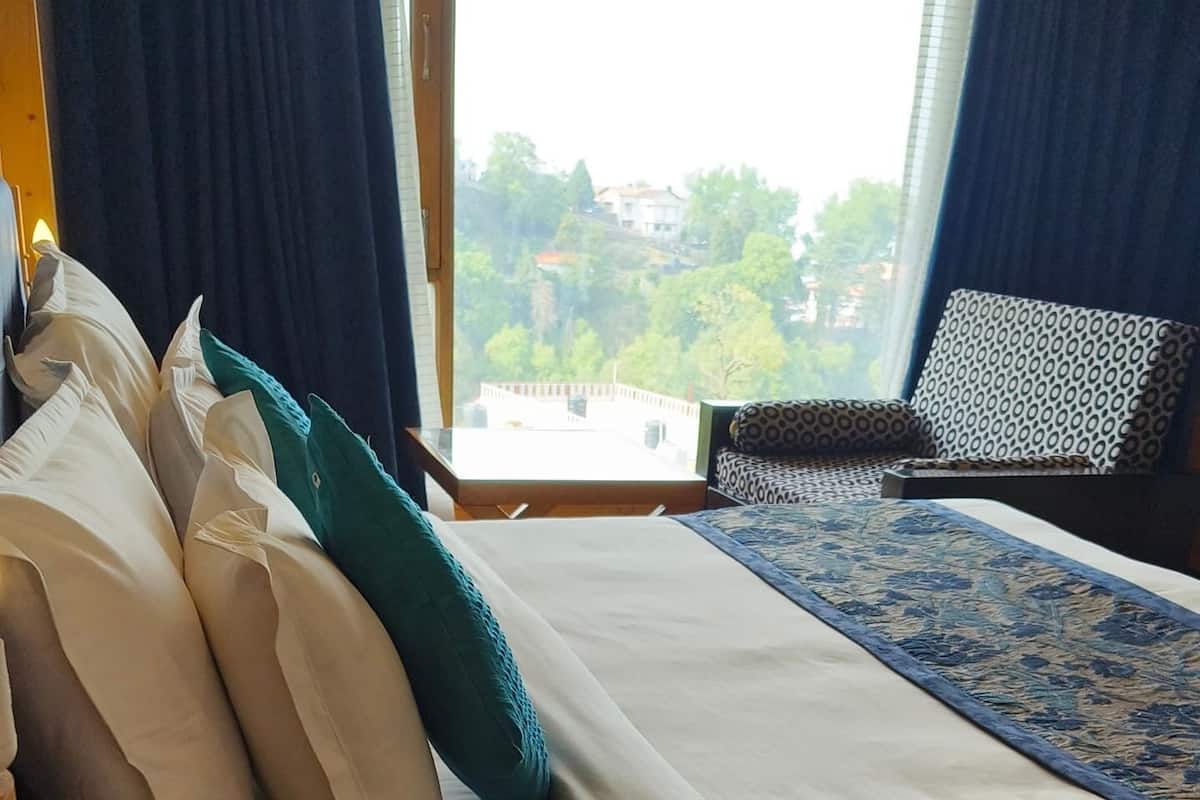 A hotel room with two beds, a small table with a telephone, and a view of the outdoors.