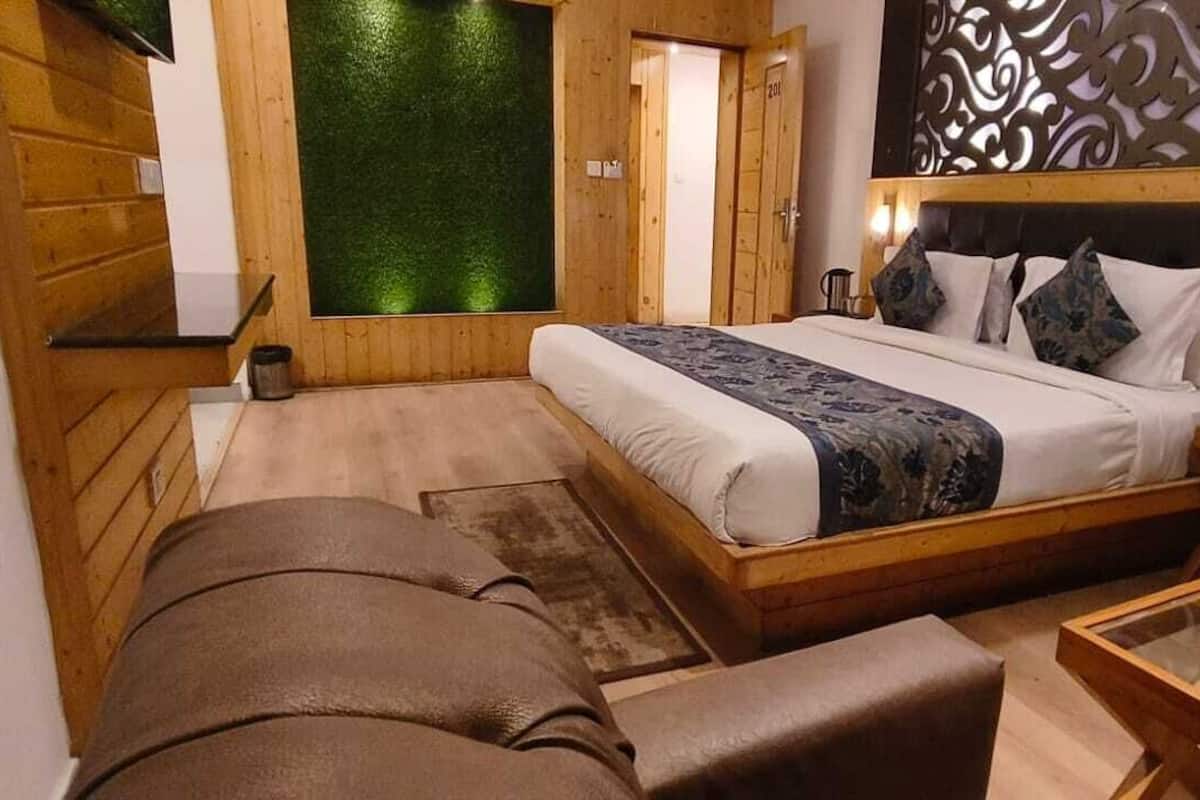 A bedroom with a large bed, a wooden headboard, a nightstand, a leather armchair, and a glass coffee table.