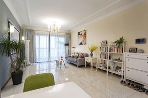 Uma sala de estar com mesa de jantar, sofá, estante de livros e um vaso de planta.