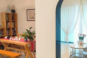 A dining area with a wooden table and benches, a bookshelf, and a potted plant.