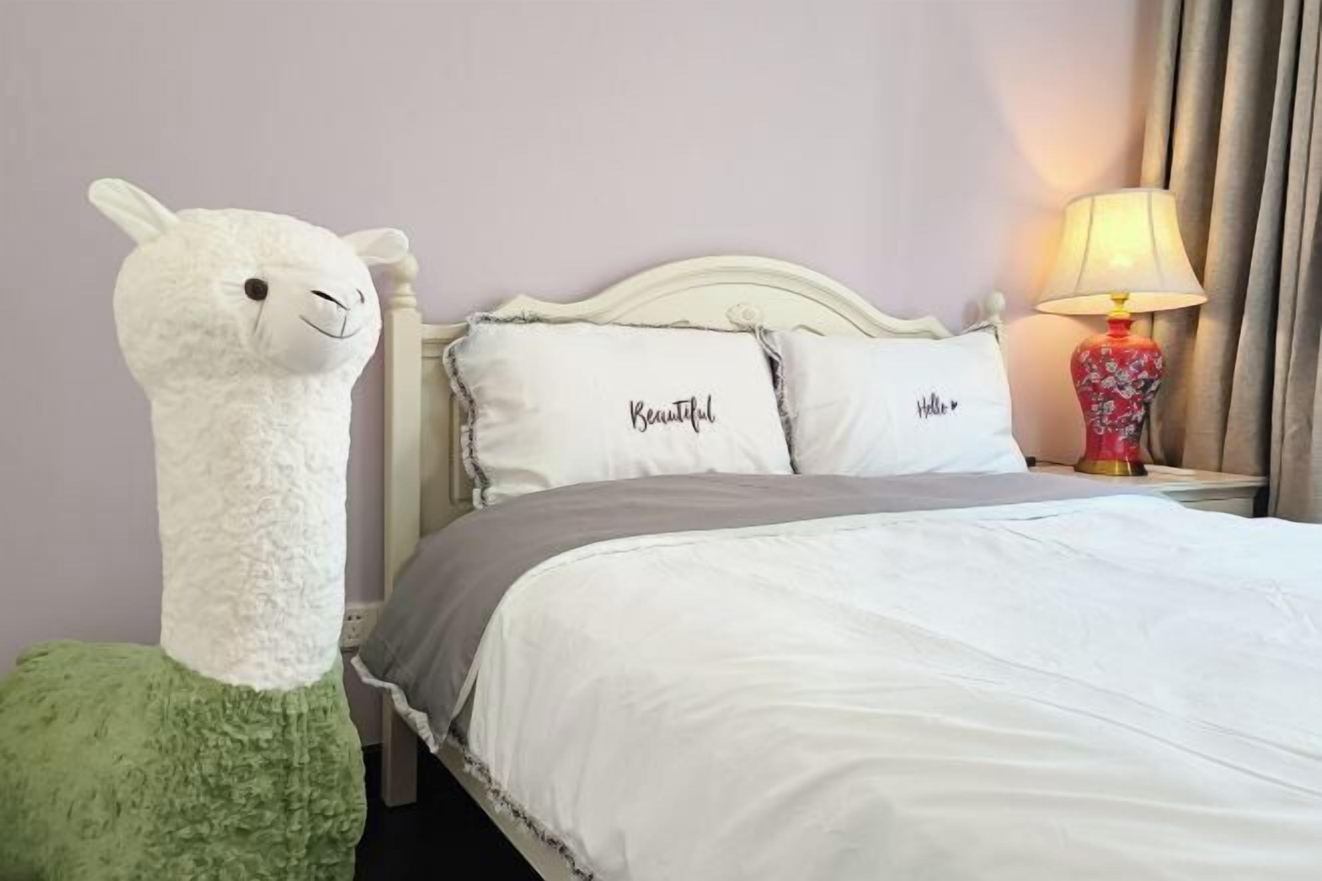 Ein Hotelzimmer mit Bett, Kissen, Lampe und einem Stofftier.