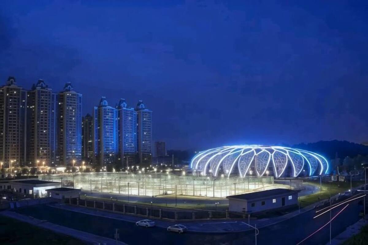 A stadium with a distinctive roof structure, surrounded by high-rise buildings.