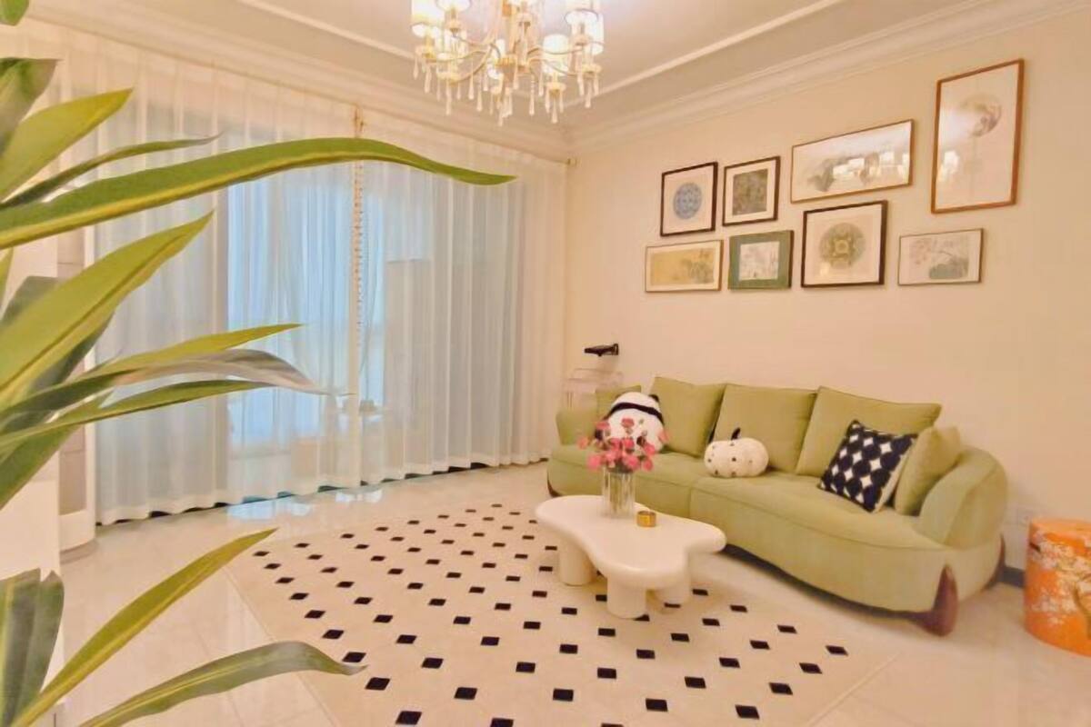 A living room with a green sofa, a white coffee table, and a patterned rug.