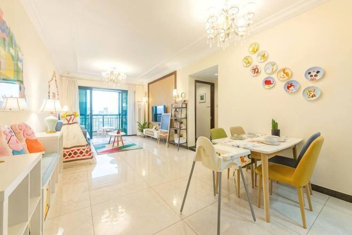 A spacious living area with a dining table, chairs, a sofa, and a TV.
