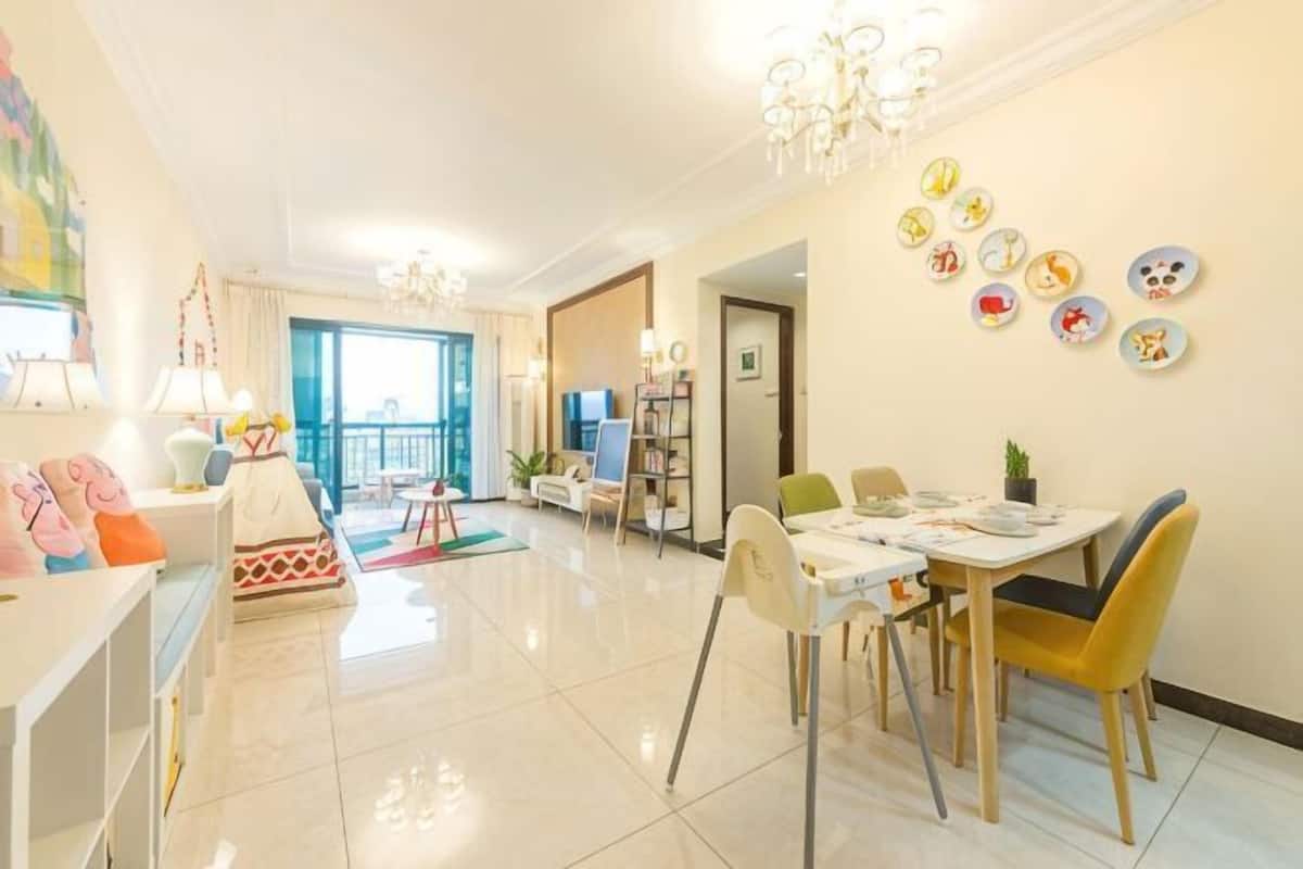 A spacious living area with a dining table, chairs, a sofa, and a TV.
