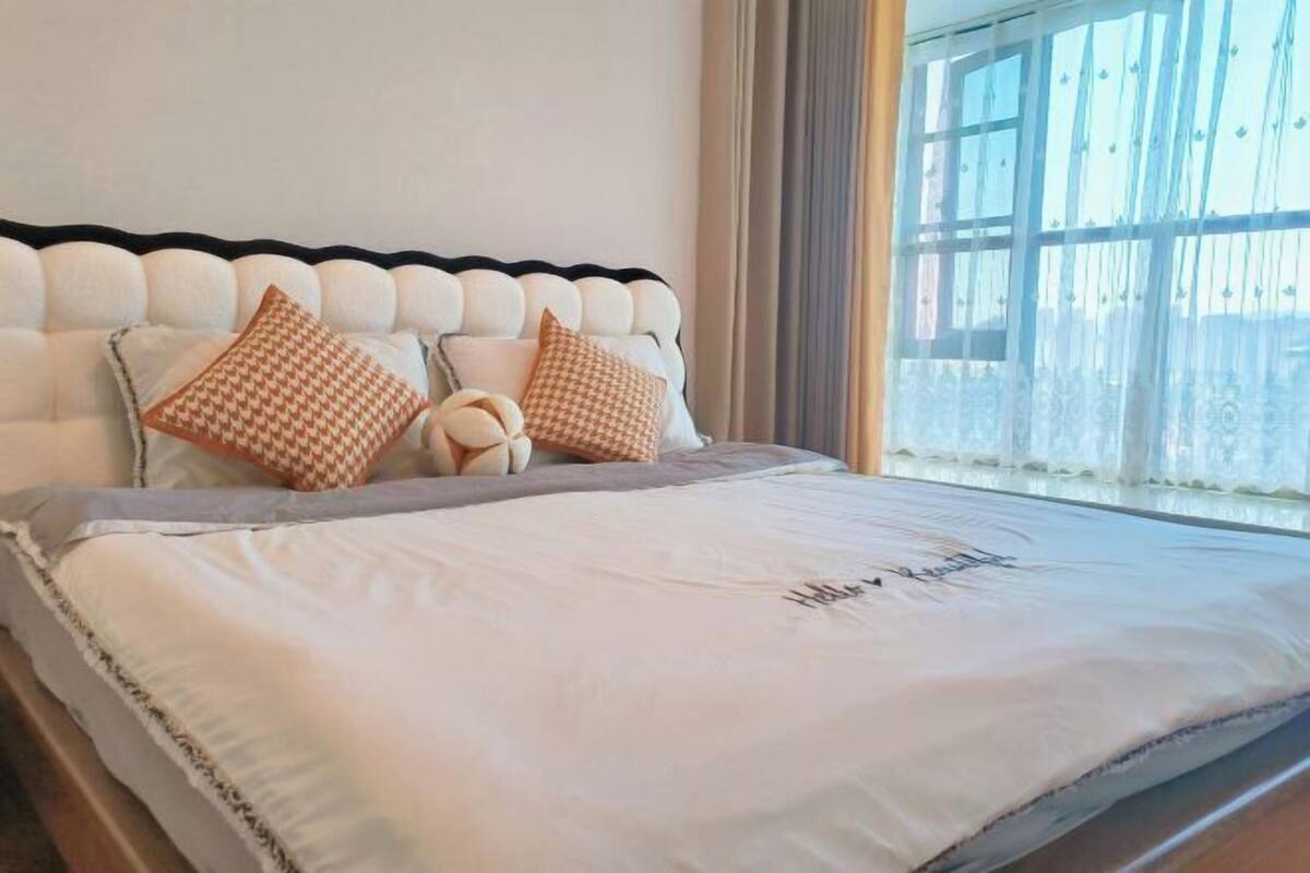 A neatly made bed with a headboard, pillows, and a blanket.