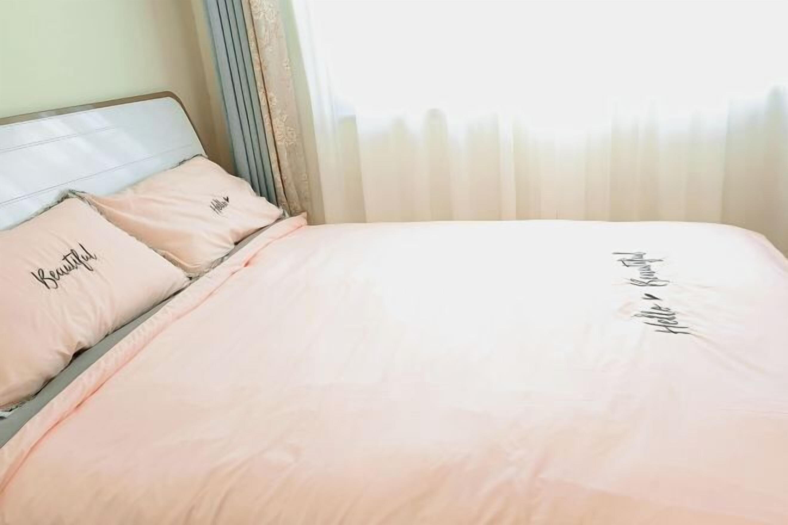A bed with a headboard, two pillows with text, and a bedspread with text.