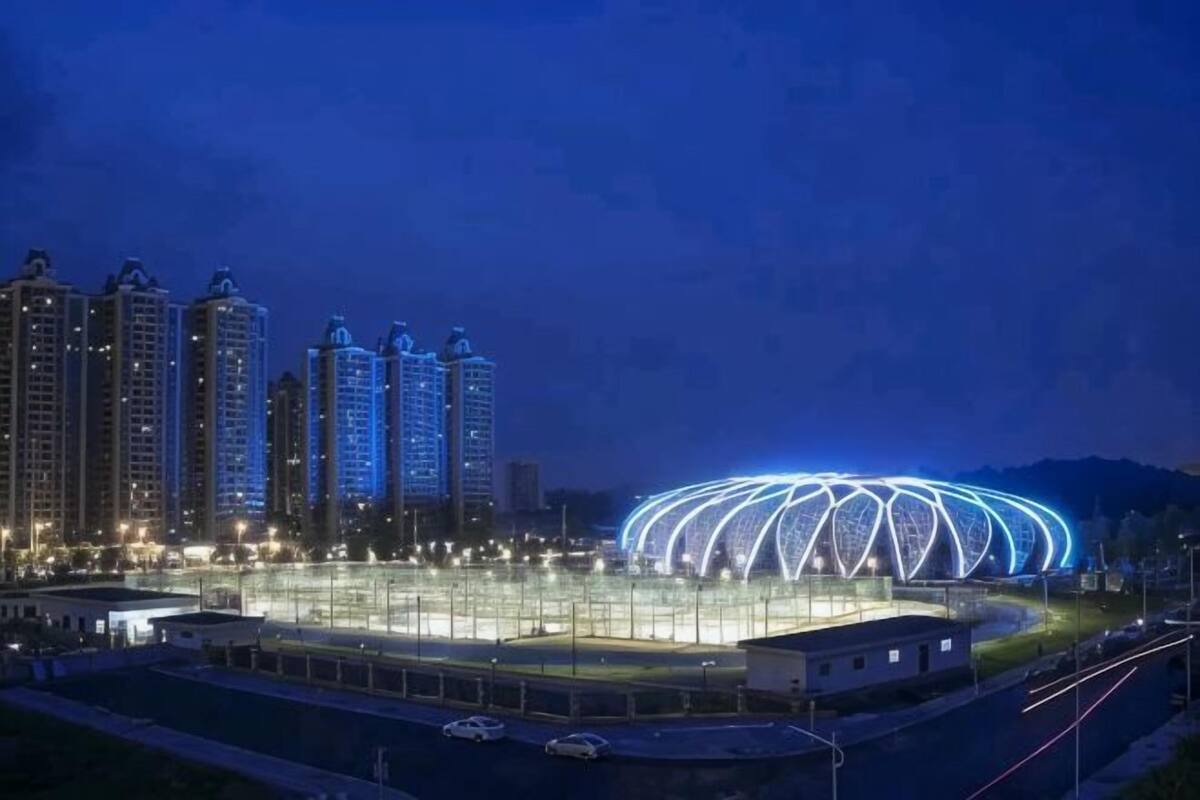 A stadium with a distinctive roof structure, surrounded by high-rise buildings.