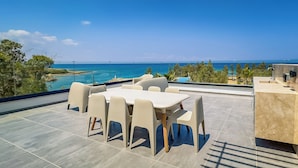 Una terraza con mesa y sillas, un lavabo y vista al mar.