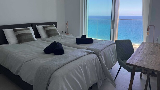 Una habitación de hotel con una cama, una silla y vista al mar.