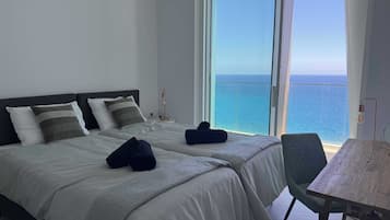 Ein Hotelzimmer mit Bett, Stuhl und Meerblick.