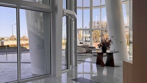 Un vestíbulo amplio con puertas de vidrio que dan a un espacio exterior, una distribución de asientos moderna y una vista despejada del paisaje circundante.