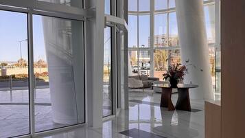 Eine großzügige Lobby mit großen Glasüren, die zu einem Außenbereich führen, einer modernen Sitzgruppe und freiem Blick auf die umliegende Landschaft.