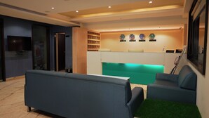 A modern living room with a flat-screen TV, a sofa, and a coffee table. - Hotel Sannidhi (Vijayawada)