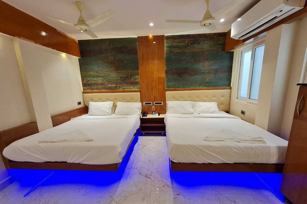 Habitación de hotel con dos camas, cabecera de madera, suelo de mármol y un cuadro en la pared.