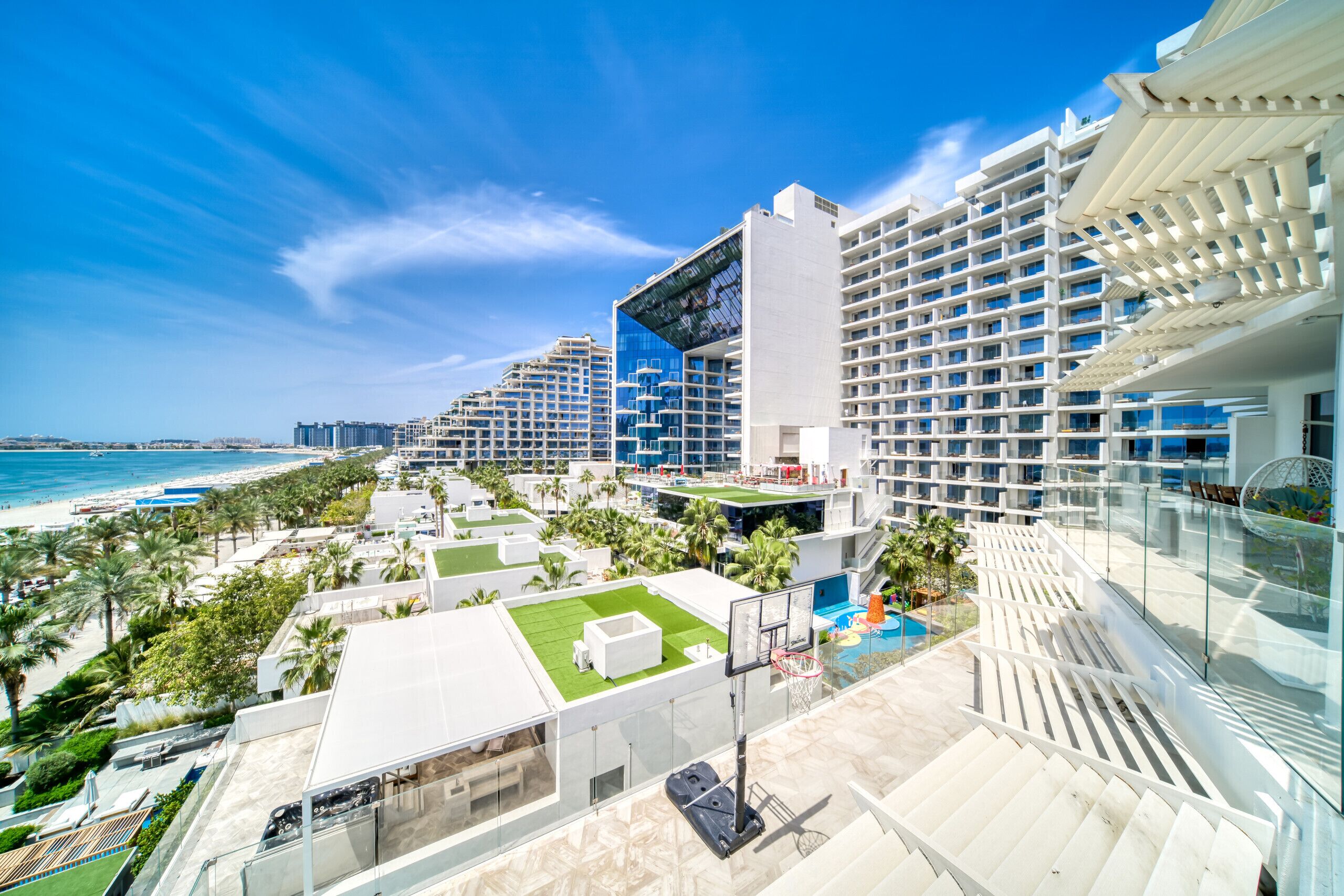 Un hôtel moderne à plusieurs étages, doté d’une piscine et offrant une vue sur la plage.