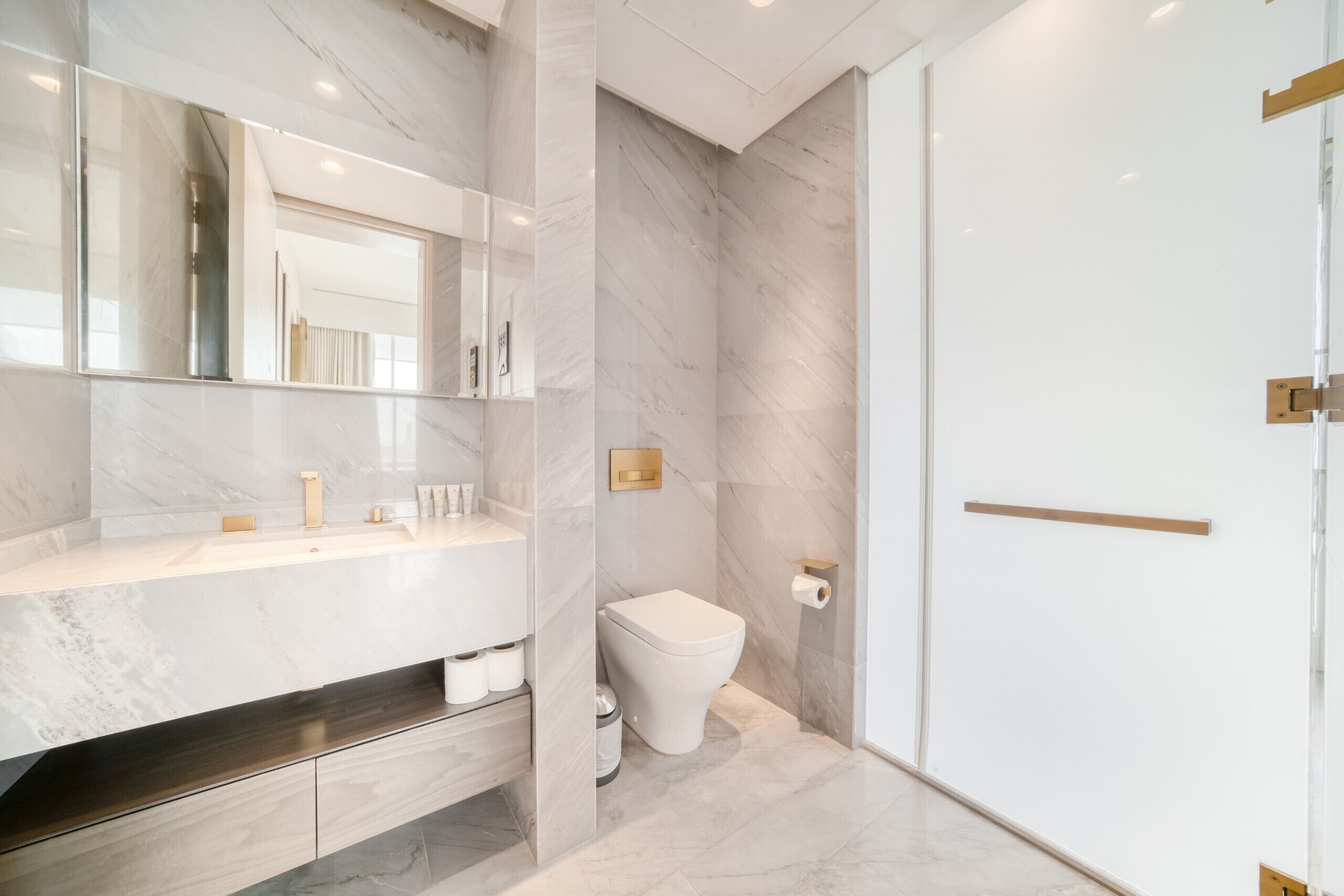 A modern bathroom with a marble vanity, a toilet, and a shower area.