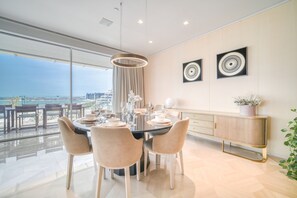 A modern dining area with a large table, chairs, and a view of the city. - FIVE Palm Jumeirah: 4BR Penthouse w/ Private Pool (Dubai)