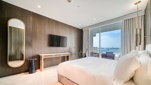 Ett modernt hotellrum med en stor säng, en platt-TV, ett skrivbord och utsikt över havet.