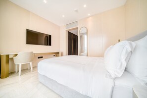 A modern bedroom with a large bed, a desk, and a chair. - FIVE Palm Jumeirah: 4BR Penthouse w/ Private Pool (Dubai)