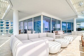Relax in this spacious living area with a large sofa and ottomans, surrounded by expansive city views.